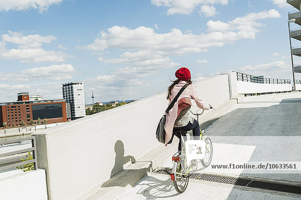 Young woman riding bicycle on parking level