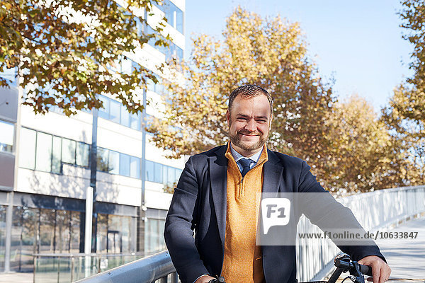 Spain  Barcelona  portrait of smiling businessman with bicycle