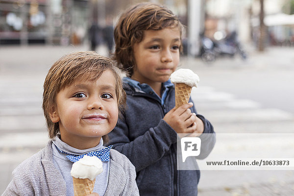 Portrait of happy little with ice cream cone and his brother in the background