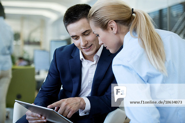 Businessman and businesswoman looking at digital tablet in office