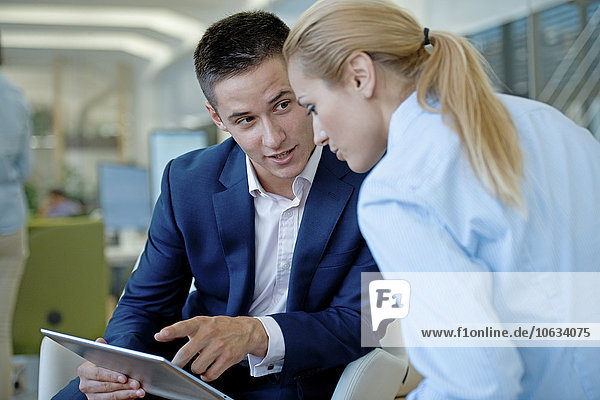 Businessman and businesswoman sharing digital tablet in office