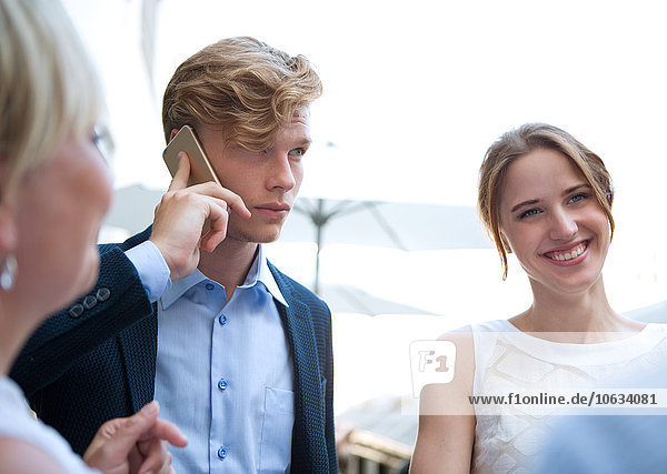 Businessman on cell phone surrounded by businesswomen
