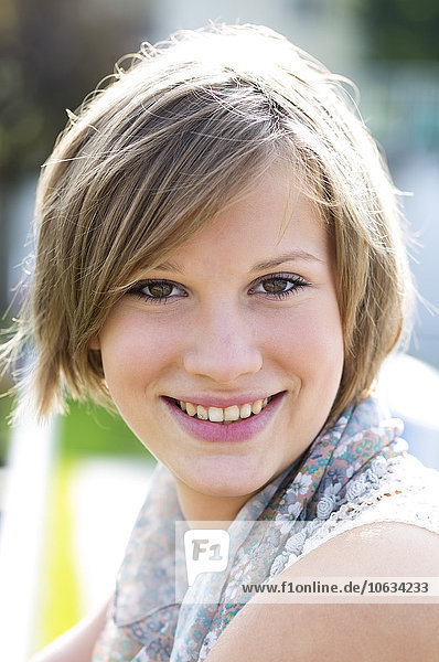 Porträt einer lächelnden blonden jungen Frau mit kurzen Haaren