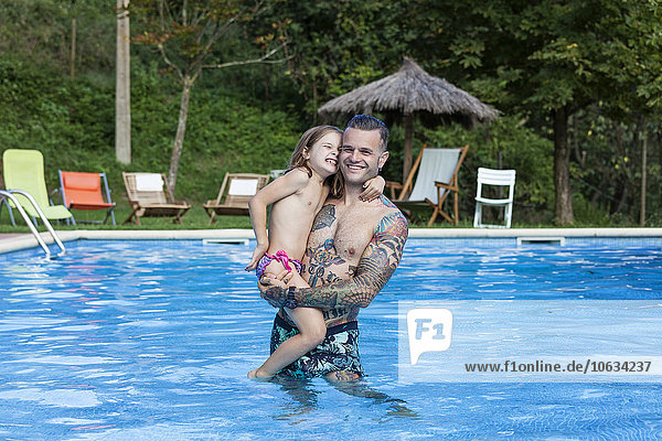 Spanien  Girona  tätowierter Mann mit seiner Tochter im Schwimmbad