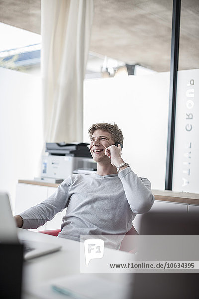 Smiling man in office on cell phone