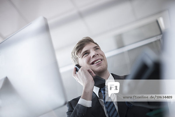 Smiling businessman talking on phone in office
