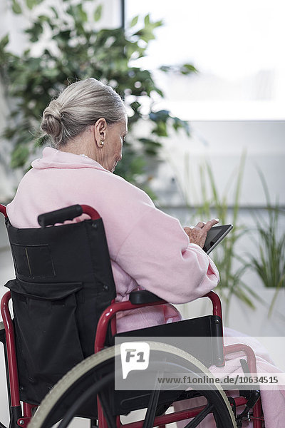 Älterer Patient im Rollstuhl mit digitalem Tablett