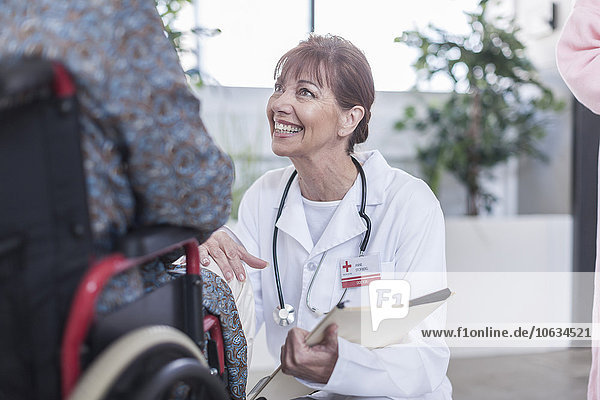 Arzt lächelt Patient im Rollstuhl an