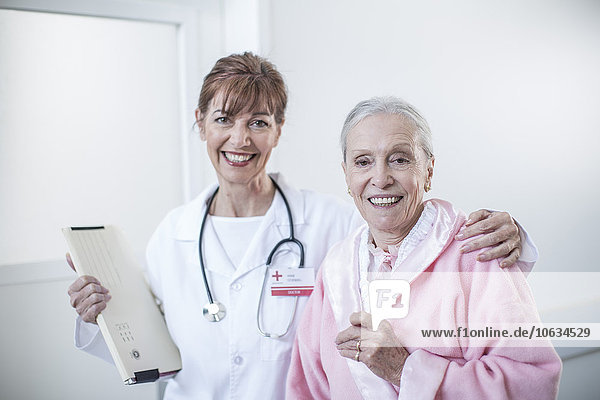 Portrait of doctor and smiling elderly patient in hospital
