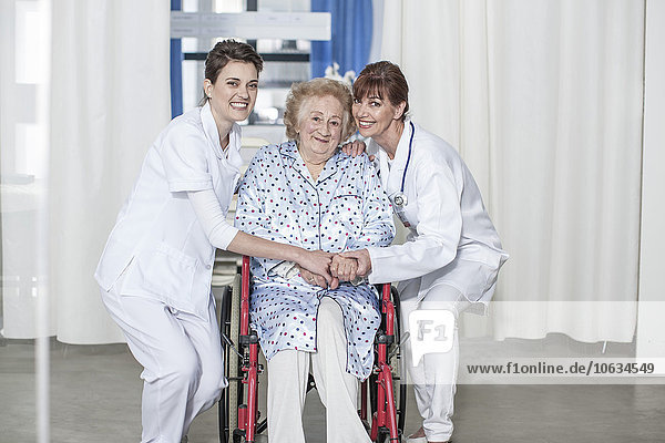 Doctor and nurse caring for elderly patient in wheelchair