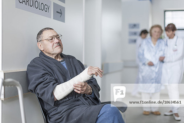 Elderly patient with arm bandage waiting in hospital