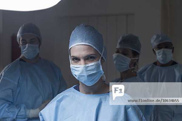 Portrait des Chirurgen mit Maske und Team im Hintergrund