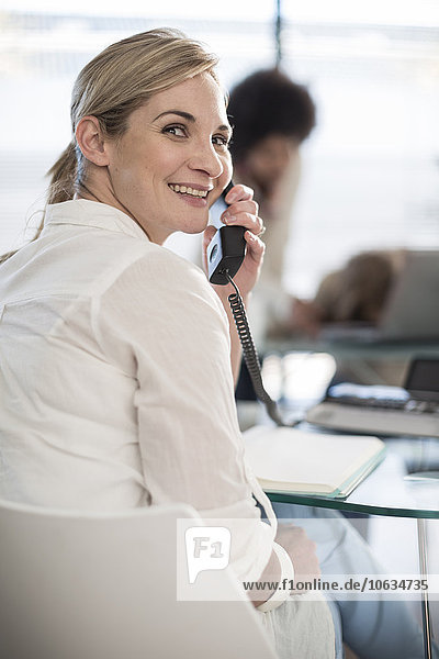 Smiling woman on the phone in office