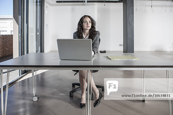 Businesswoman sitting at desk using laptop