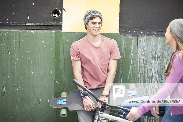 Junger Mann mit Skateboard lächelndes Teenagermädchen