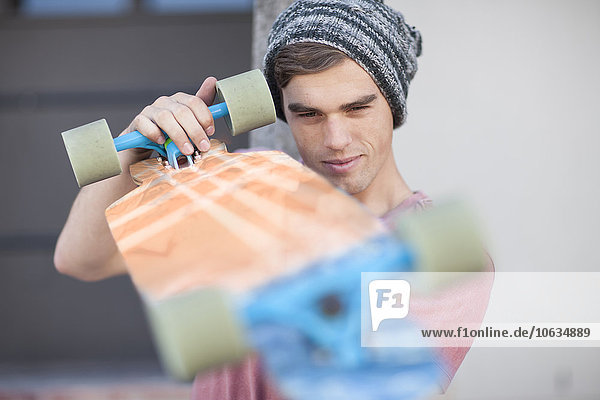 Junger Mann bei der Untersuchung seines Skateboards
