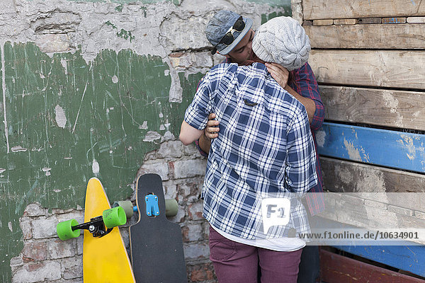 Junges Paar mit Skateboard Umarmen und Küssen