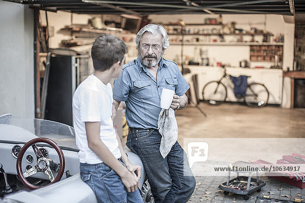 Grandfather and grandson having a break from restoring a car