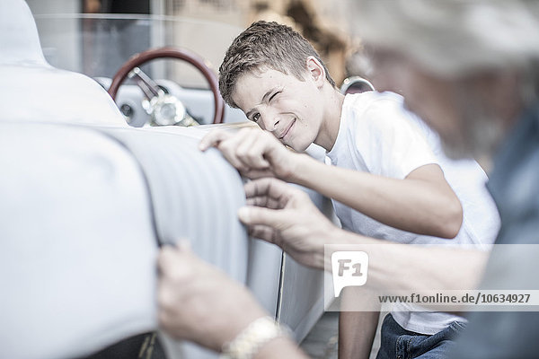 Boy with grandfather scrutinizing car