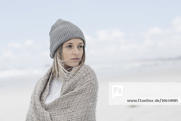 Portrait of woman wearing beanie and wrap on the beach