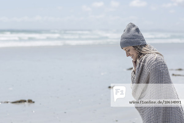 Woman wearing beanie and wrap on the beach