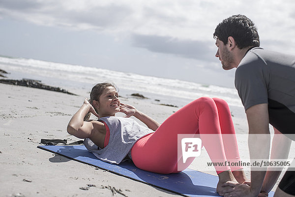 Young man and woman exercising on beach