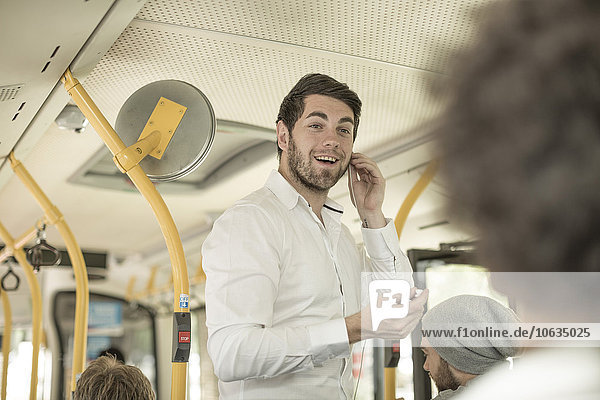 Young man talking on the phone in a city bus
