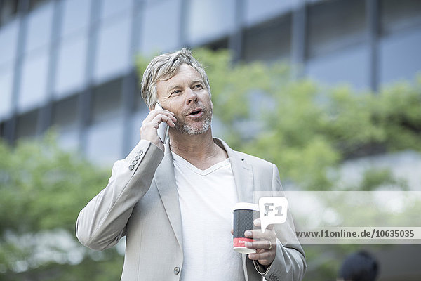 Mature man talking on the phone  holding coffee cup