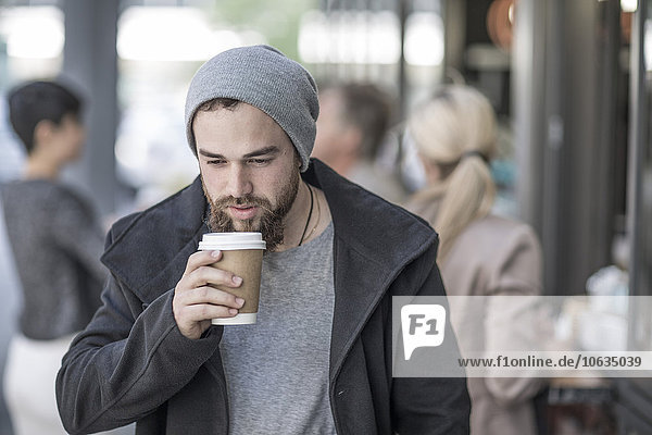 Young man drinking takeaway coffee in the city