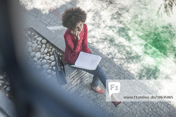 Young businesswoman sitting outdoors  talking on the phone