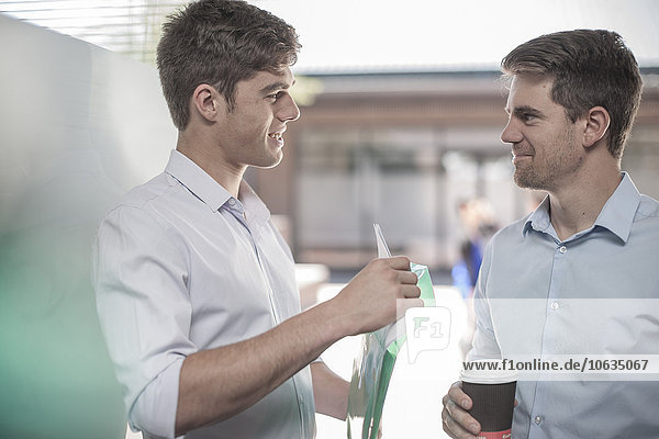 Colleagues talking in the street  holding coffee cups