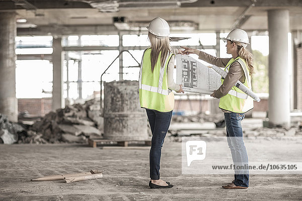 Zwei Frauen in Arbeitsschutzbekleidung besprechen Bauplan auf der Baustelle
