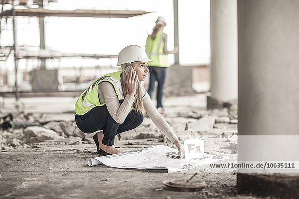 Frau in Arbeitsschutzbekleidung am Handy auf der Baustelle
