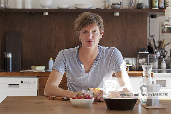 Junger Mann am Esstisch mit Frühstück  Porträt