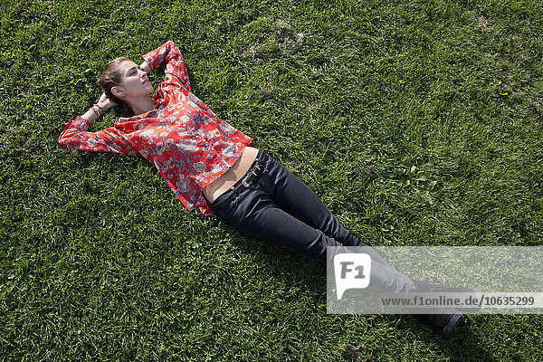 Junge Frau auf Gras im Park liegend