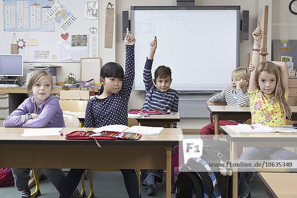 Students raising their hands in classroom