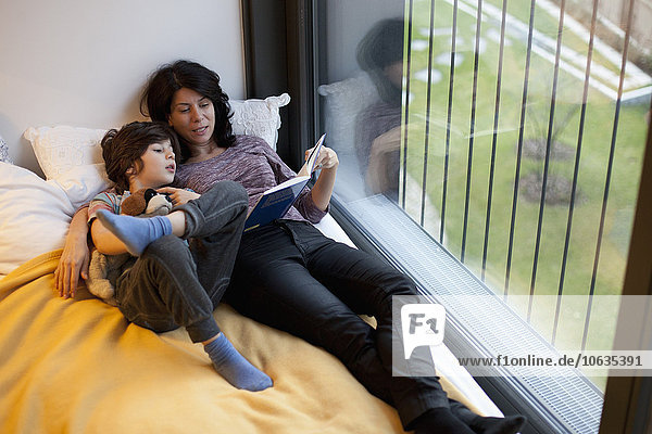 Mutter und Sohn liegen auf dem Bett und lesen Buch