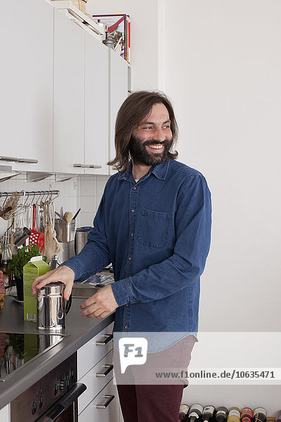 Lächelnder Mann schaut weg  während er an der Küchentheke steht.