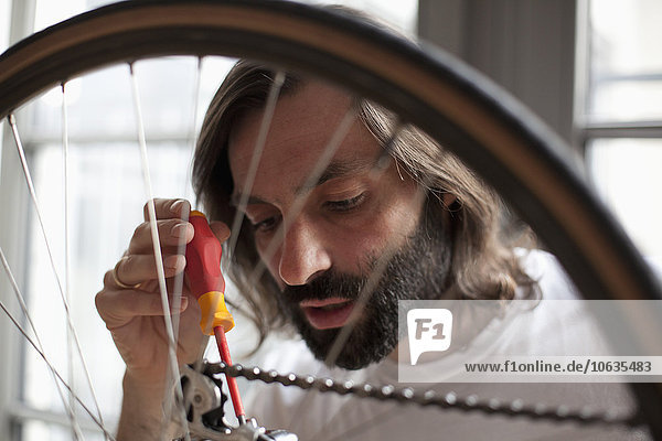 Mittlerer Erwachsener Mann repariert Fahrrad zu Hause