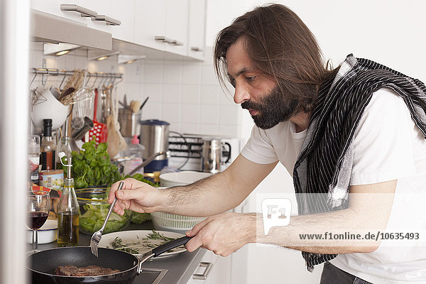 Mittlerer erwachsener Mann bei der Zubereitung von Fleisch in der heimischen Küche