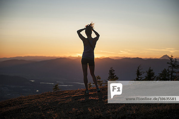 Durchgehende Rückansicht der auf dem Berg stehenden Frau bei Sonnenaufgang