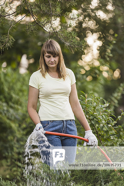 Frau beim Gießen von Pflanzen auf dem Hof