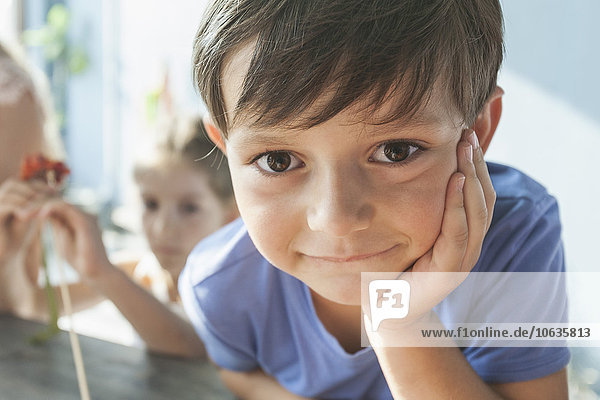 Close-up portrait of cute boy leaning on table at home