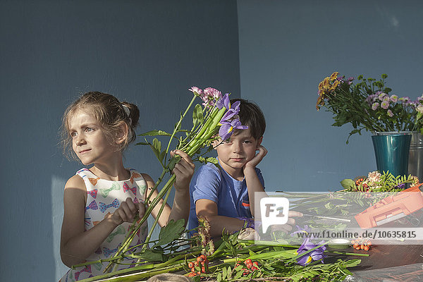 Geschwister arrangieren Blumen am Tisch