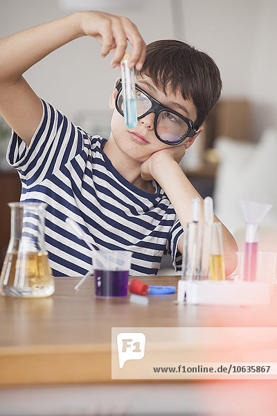 Junge mit Schutzbrille beim Blick auf das Reagenzglas im Haus