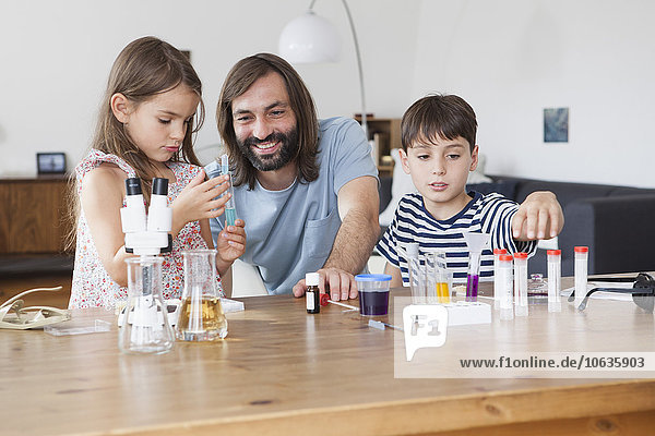 Vater und Kinder beim wissenschaftlichen Experiment auf dem Tisch im Haus
