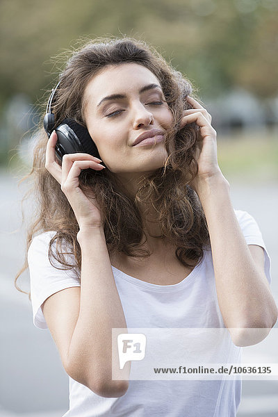 Young woman enjoying listening music outdoors