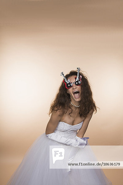 Aufgeregte Braut in gitarrenförmiger Brille schreit vor farbigem Hintergrund