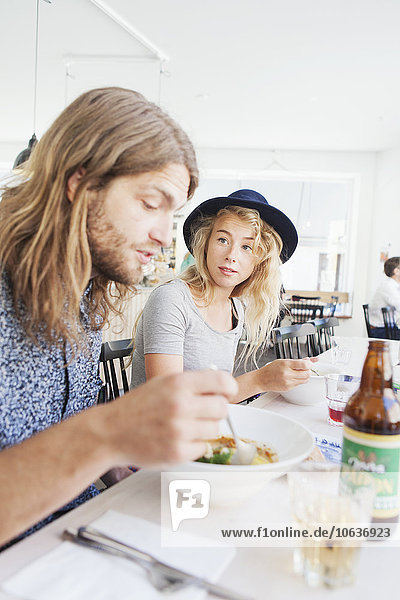 Woman looking at man while having food at restaurant table