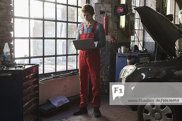 Mechanic using laptop by window at garage